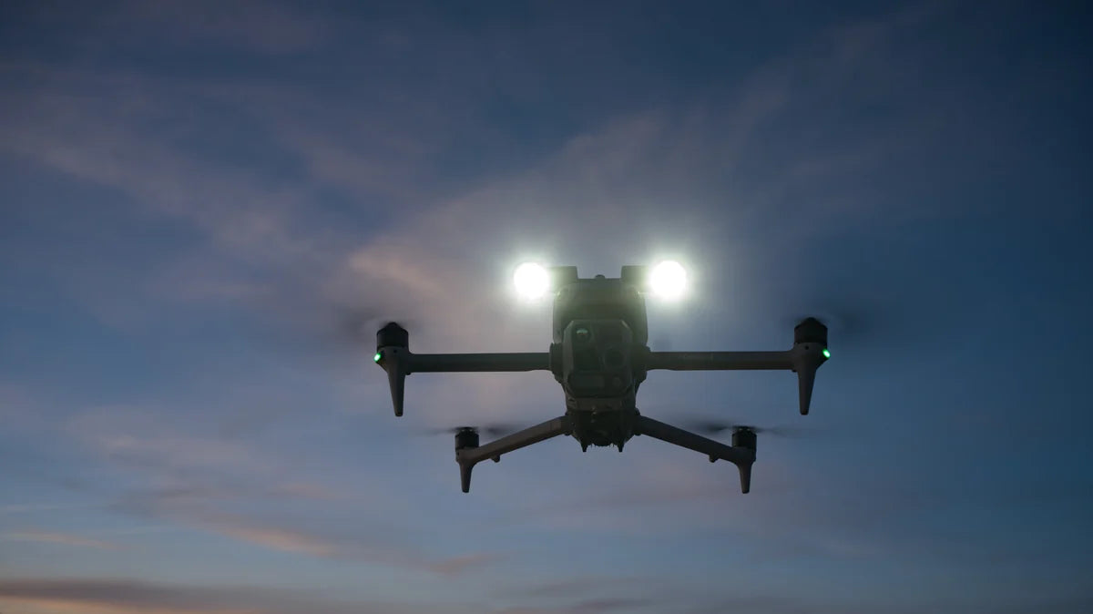 Matrice 4 Series drone airborne at dusk with its two spotlight lamps illuminated